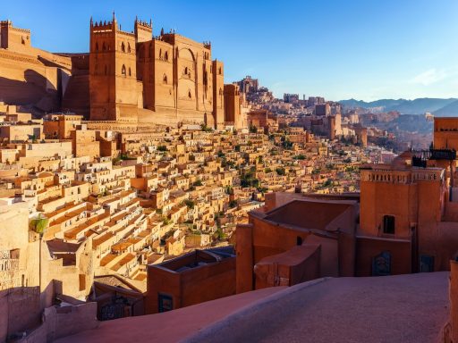 Historic sandstone buildings and terraces in a mountainous landscape.