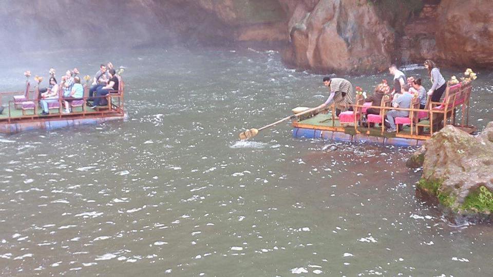 Boat ride at Waterfall Two wooden rafts on a misty river, with groups of people enjoying the scenic view.