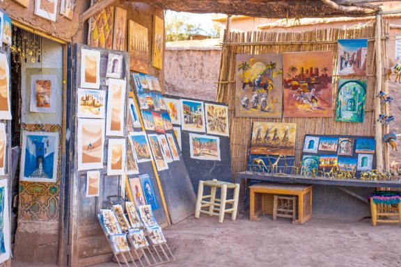 Artisan market showcasing diverse paintings and crafts in a sunlit room.