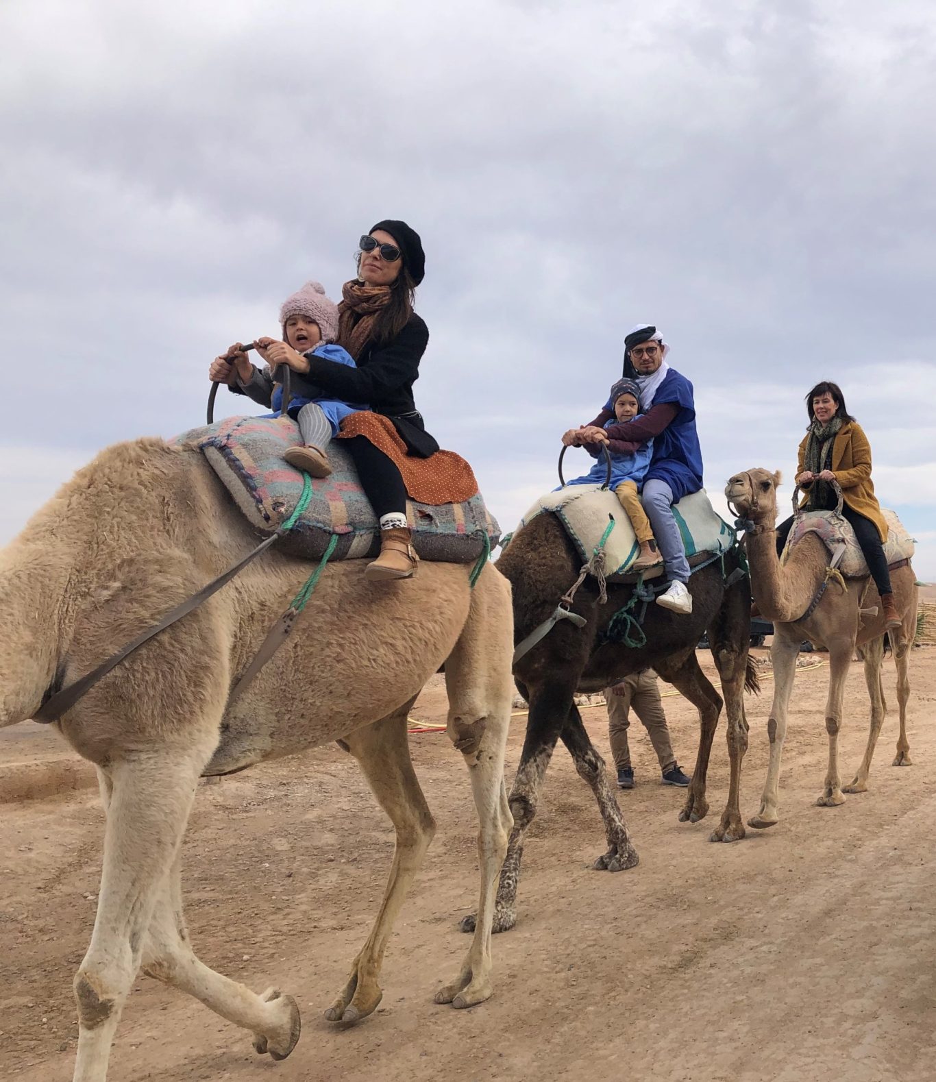 A group of people riding camels in a desert landscape.