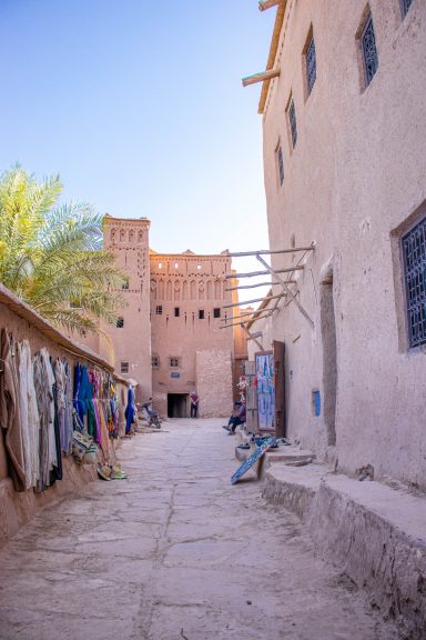 Narrow alleyway between traditional earthen buildings, with blue skies overhead.